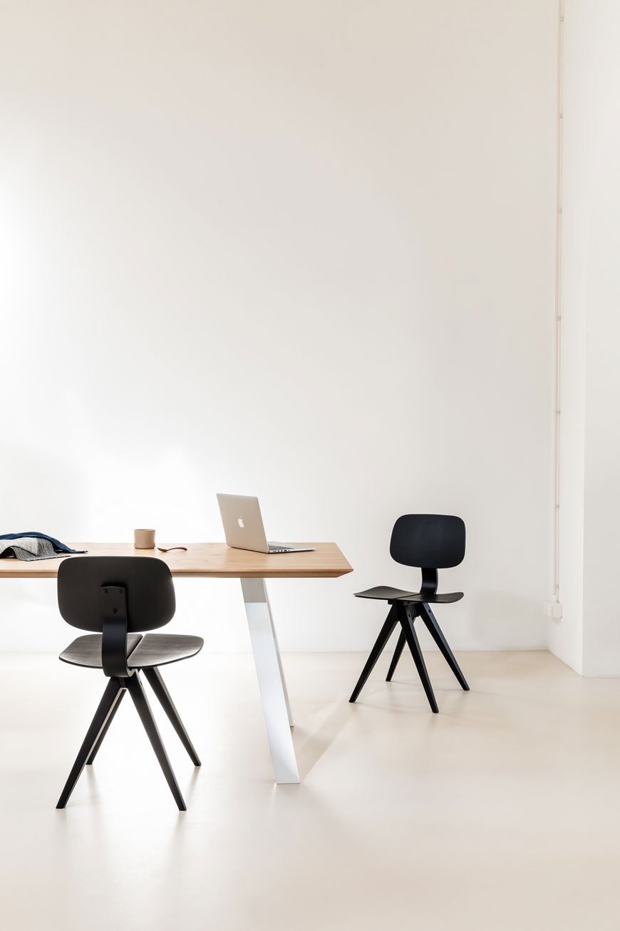 The black Mosquito chair sits in a minimalist office space, designed by Rex Kralj.