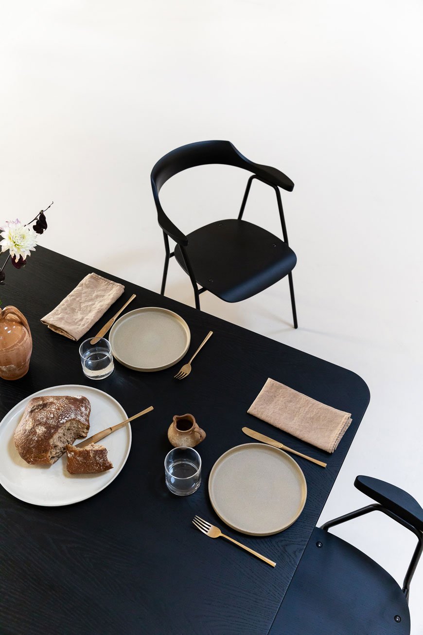 Minimalist black dining chair designed by Rex Kralj and a simple, minimalist table setting.