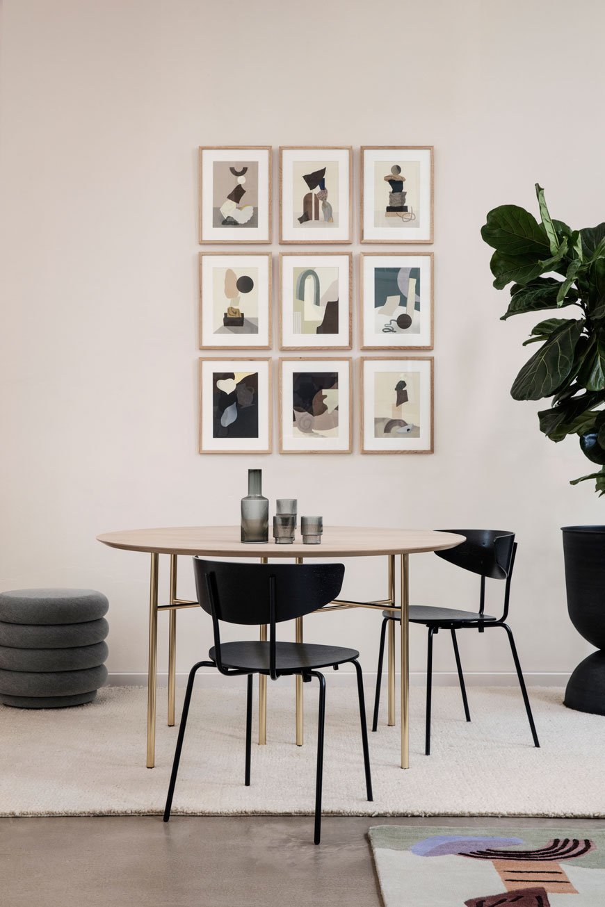 A gallery wall of abstract art in a dining room setting, designed by Ferm Living. 