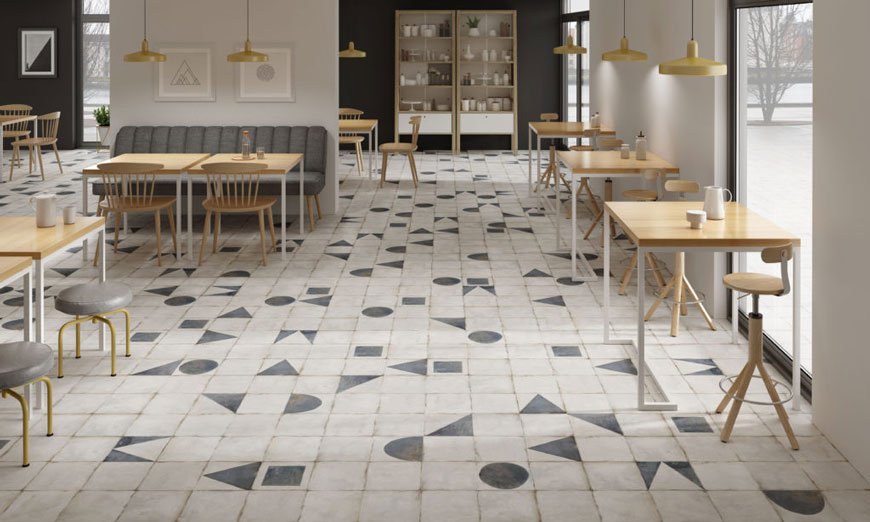 Worn, vintage style monochrome hallway floor tiles interspersed with pale black shapes.