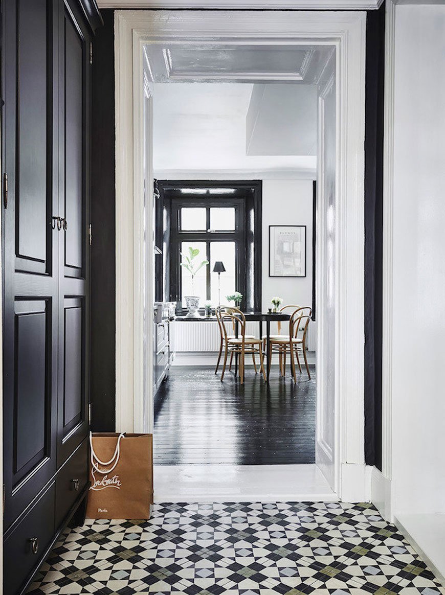 A very monochrome apartment featuring highly patterned monochrome hallway floor tiles with touches of blue and green.