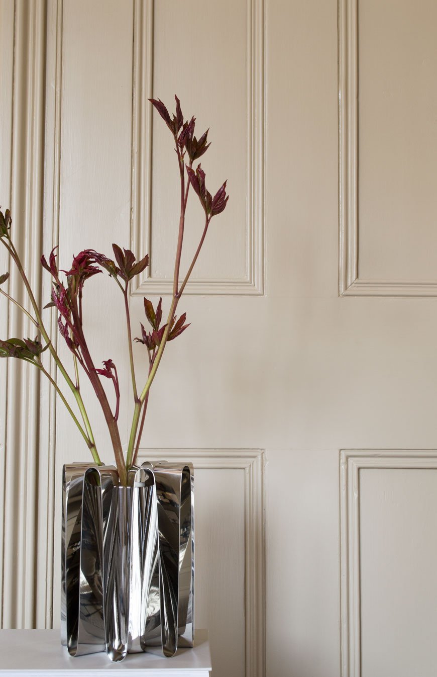Frequency collection steel vase by Georg Jensen against a beige panelled door