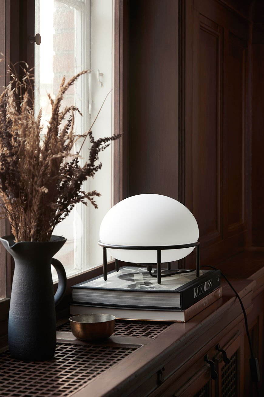 The Pump lamp with a black metal frame and opaline glass globe inspired by hot air balloons and designed for Woud.