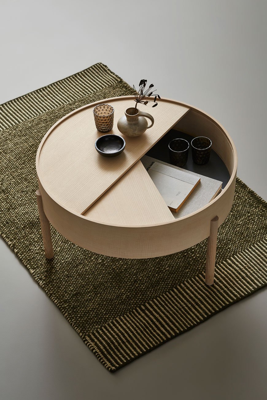 The round ash wood Arc coffee table with a storage cubby inside, designed for Woud. 