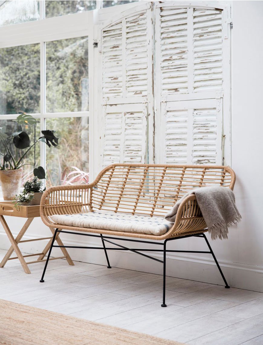 Stylish, sustainable outdoor furniture in woven bamboo with black steel legs, sitting in a garden room with white washed walls