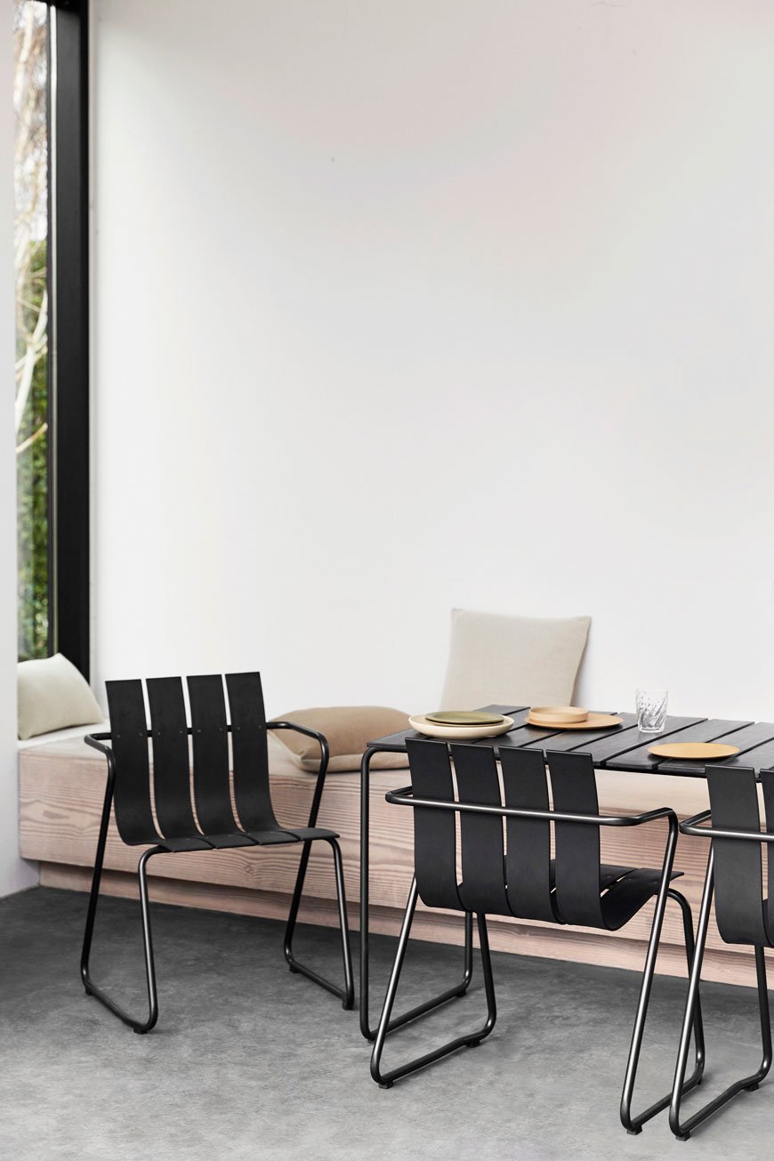 black recycled plastic outdoor furniture with slatted seats in a bright and open interior. 