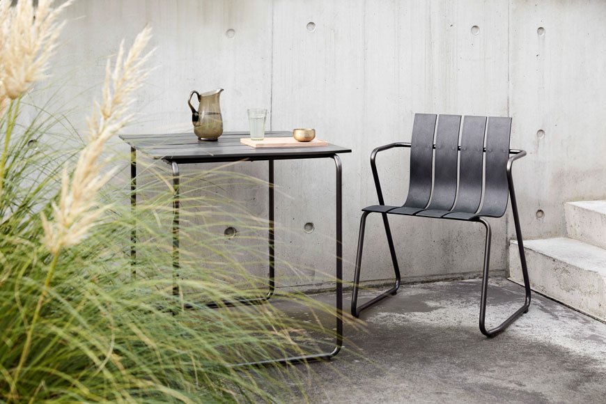 Award winning outdoor furniture designed by Mater, the Ocean chair sits against a concrete garden wall with pampas grasses.