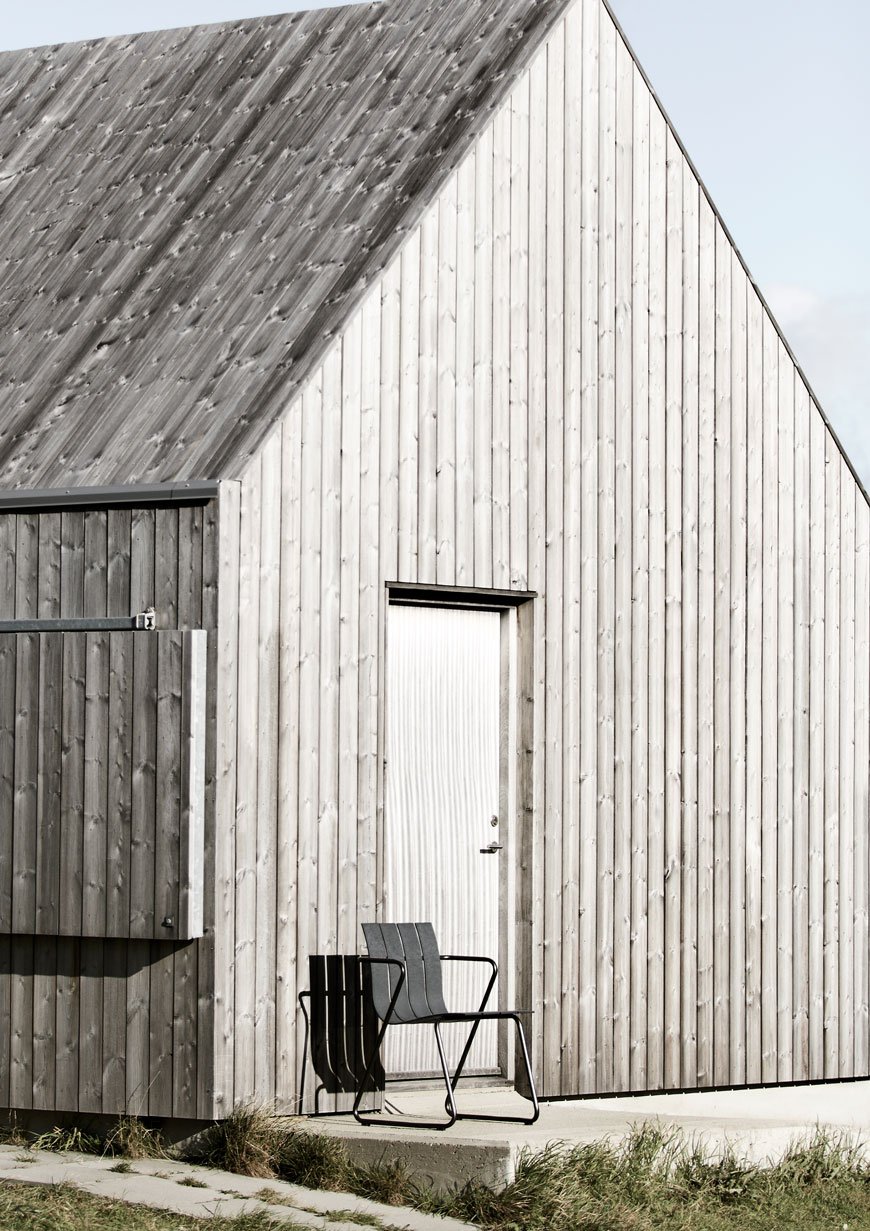 Black recycled plastic outdoor furniture sitting against a weathered grey cabin.