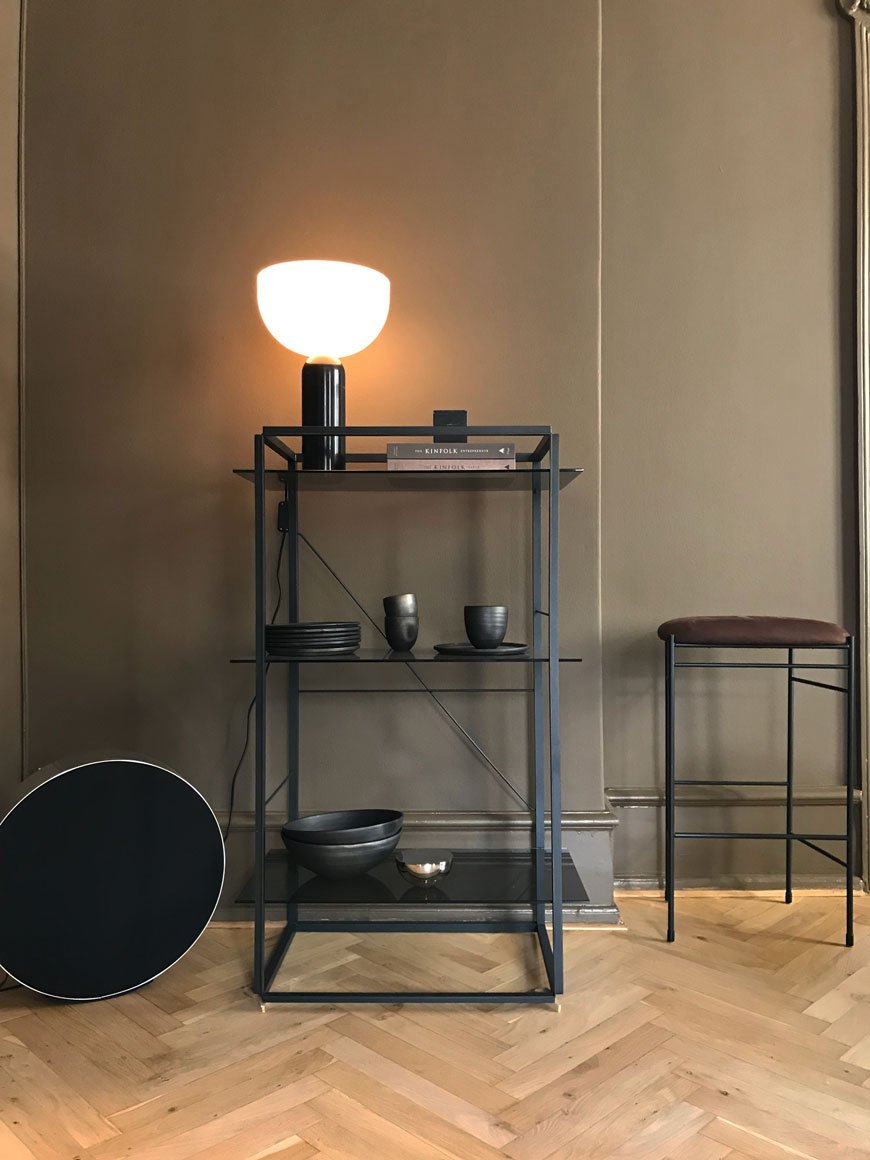 A round Bang and Olufsen speaker sits beside a black metal shelving unit at the New Works showroom.
