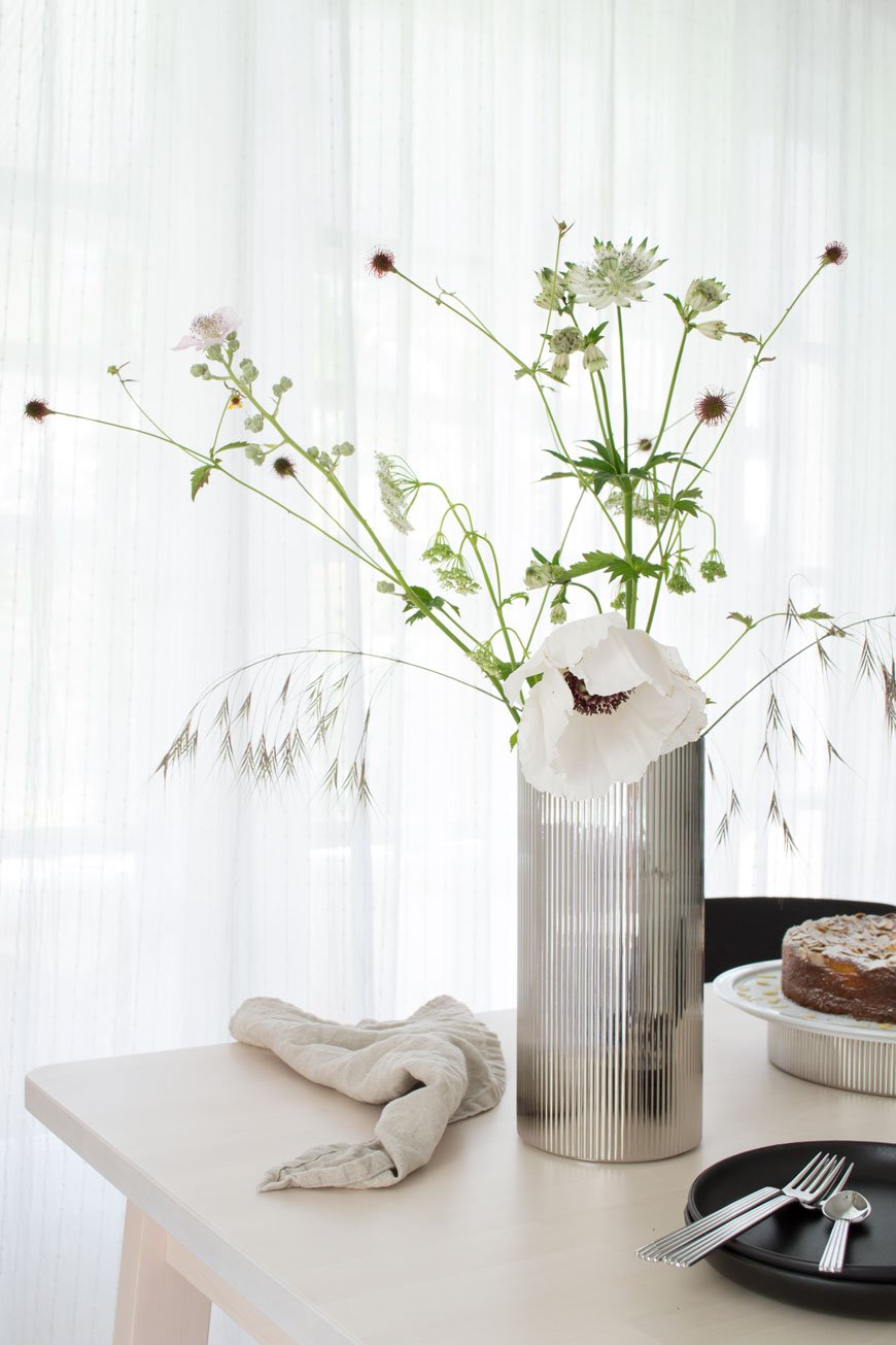 Loose white garden and wild flowers styled in a stainless steel ridged vase by Sigvard Bernadotte.
