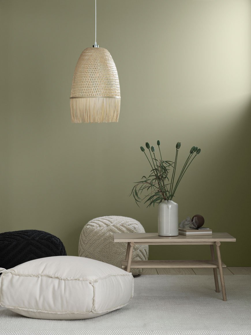 Soothing, natural home accessories styled in a with a soft green living room with a low level rattan pendant lamp.