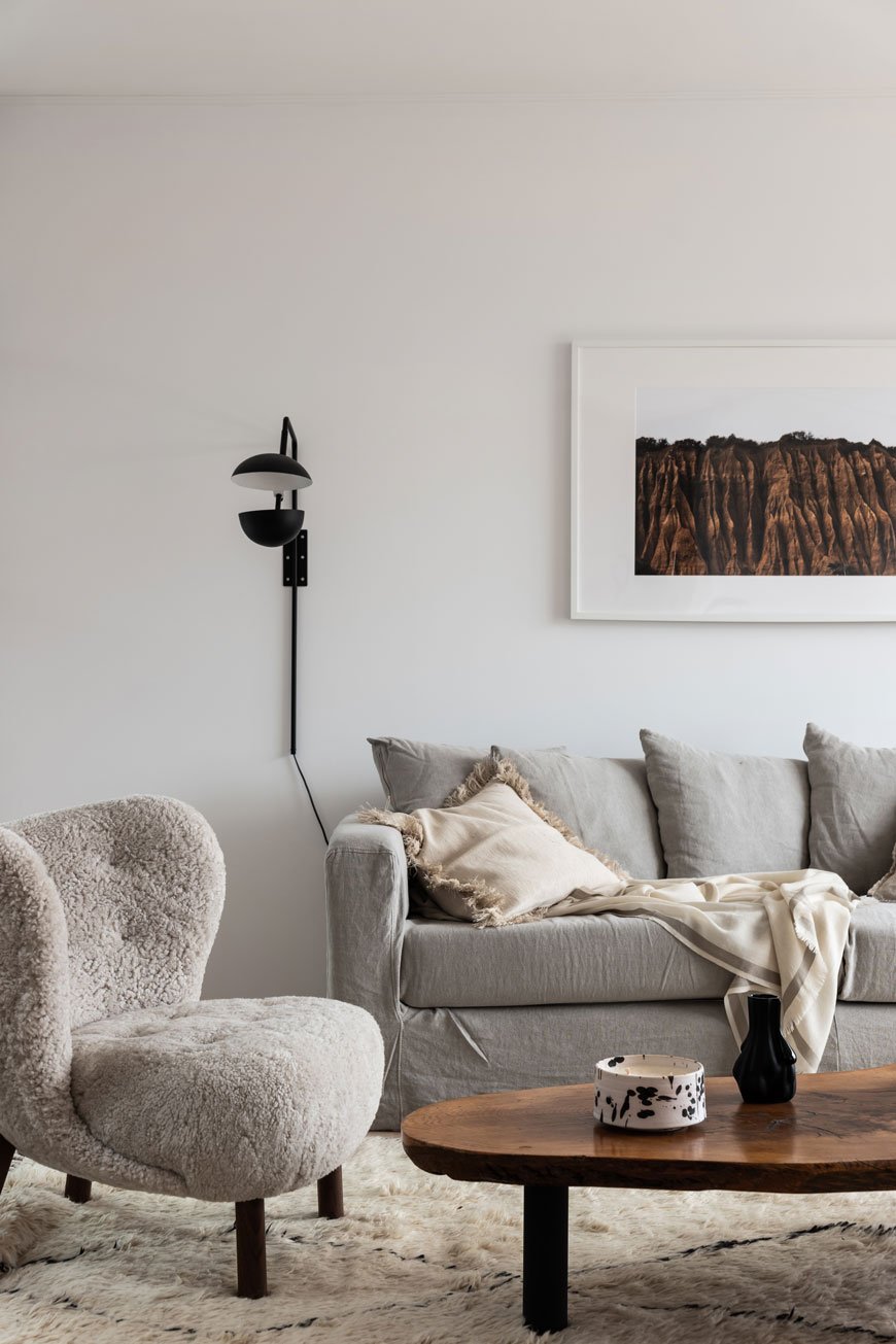 A cosy Nordic living room designed by Blooc with a grey linen sofa and fluffy Little Petra chair by &Tradition. 