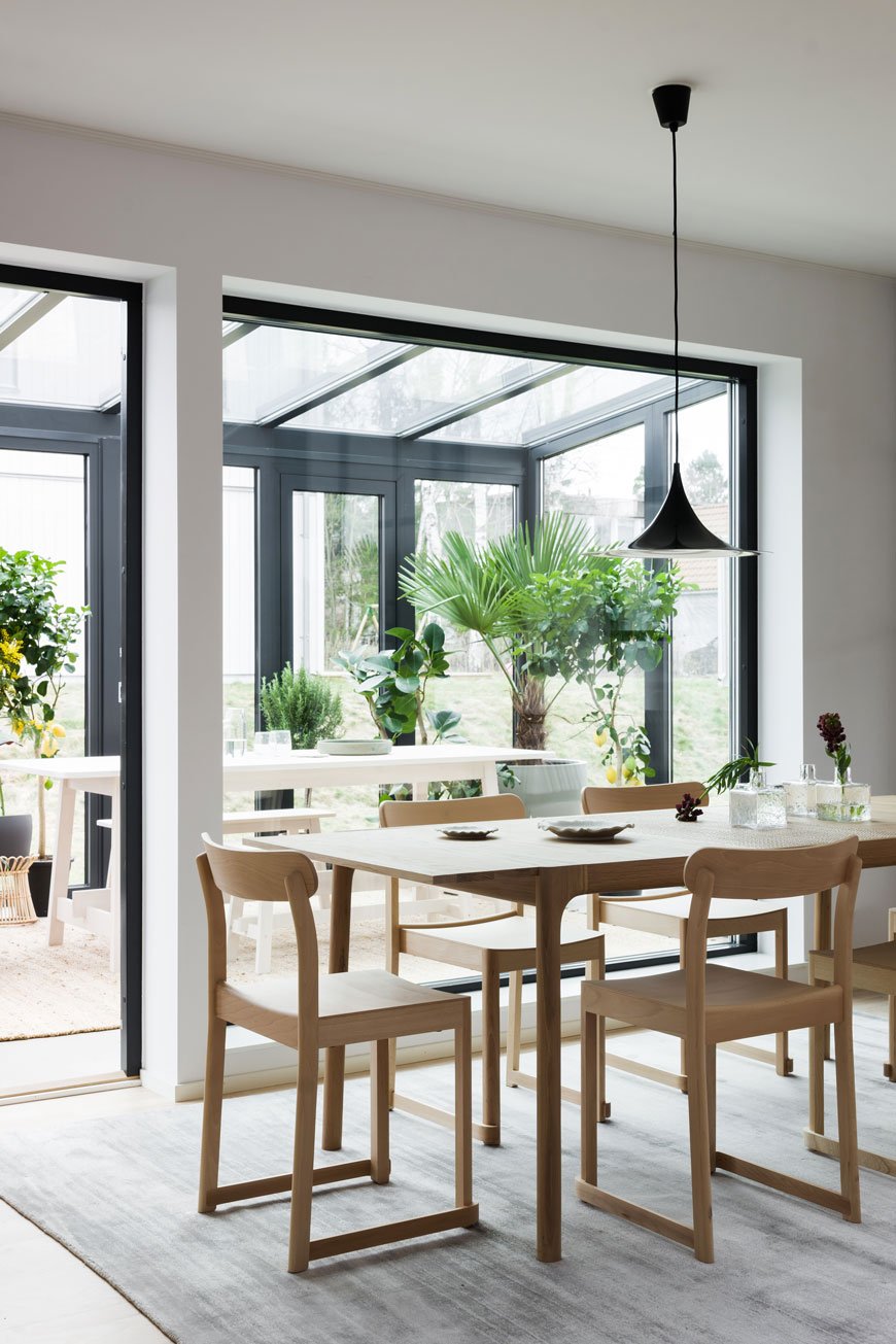 A beautiful, light filled dining room with oak dining table looks out into a contemporary garden room build by Blooc. 