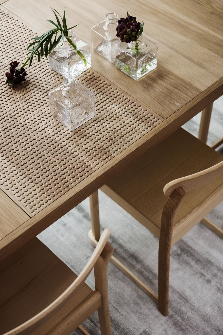 Details in an oak dining table styled with little bud vases inside the Parkhusen project by Blooc. 