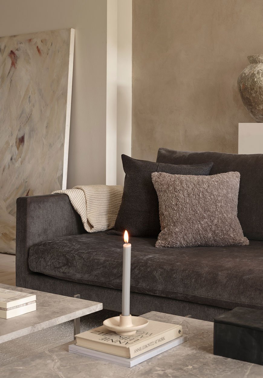 A contemporary brown sofa styled with textured neutral cushions and marble coffee tables for Zara Home. 