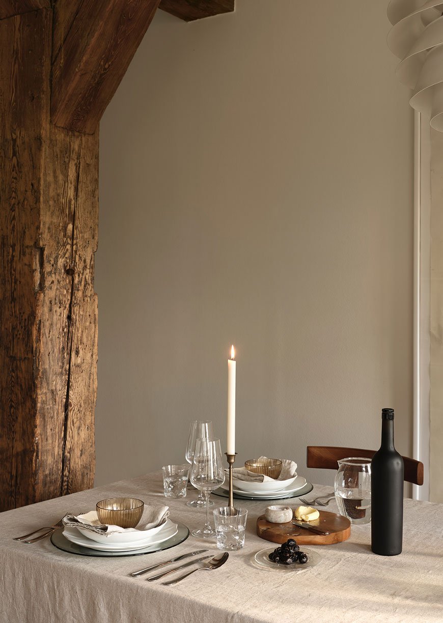 A rustic table set with linen table cloth, brass candlestick and amber glassware from Zara Home.