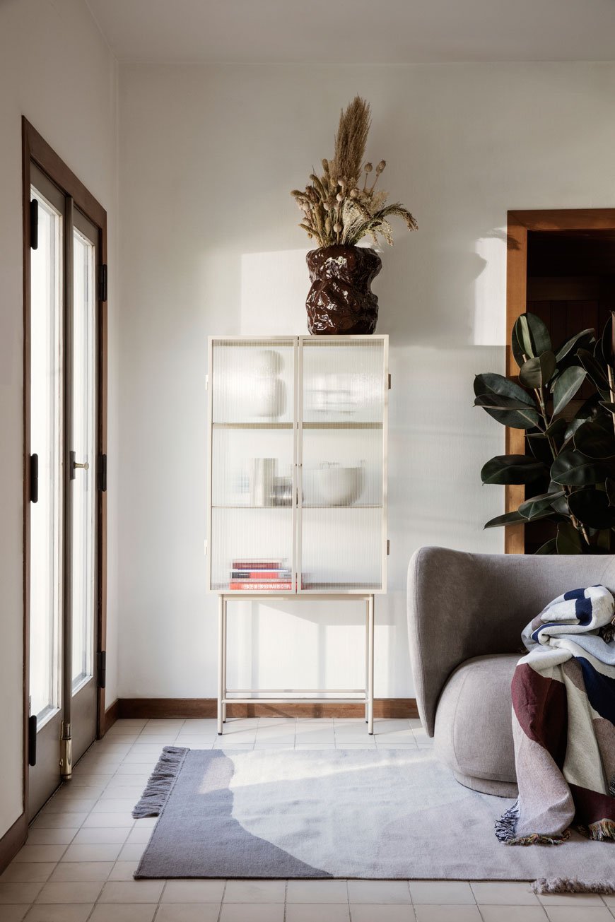 The Ferm Living Haze Vitrine in a Cashmere white styled in a Nordic living space with houseplants. 