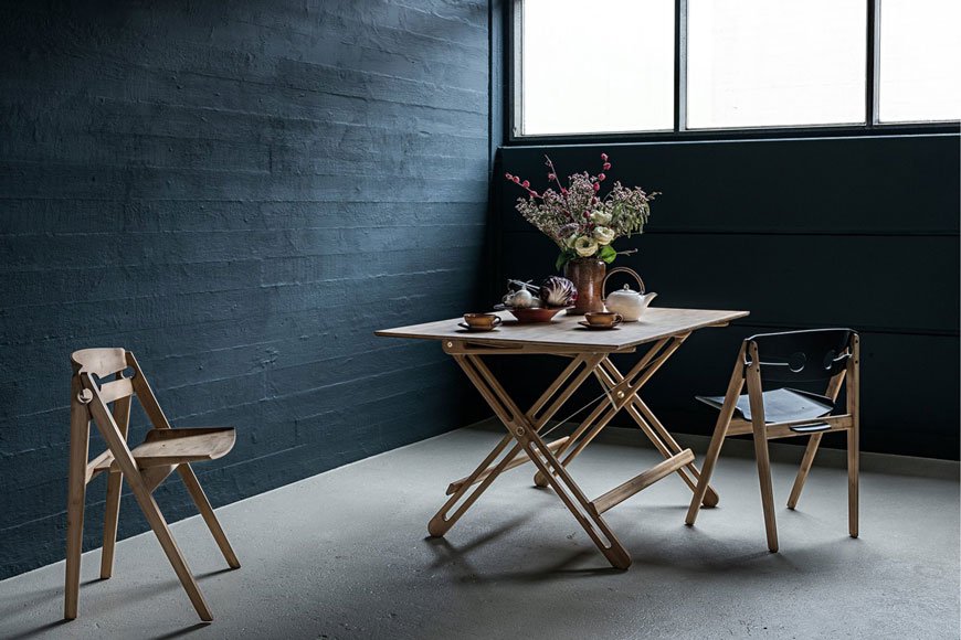 A dark and moody dining room styled with a Hagen folding dining table and chairs made from sustainable bamboo, from Pepper Sq. 