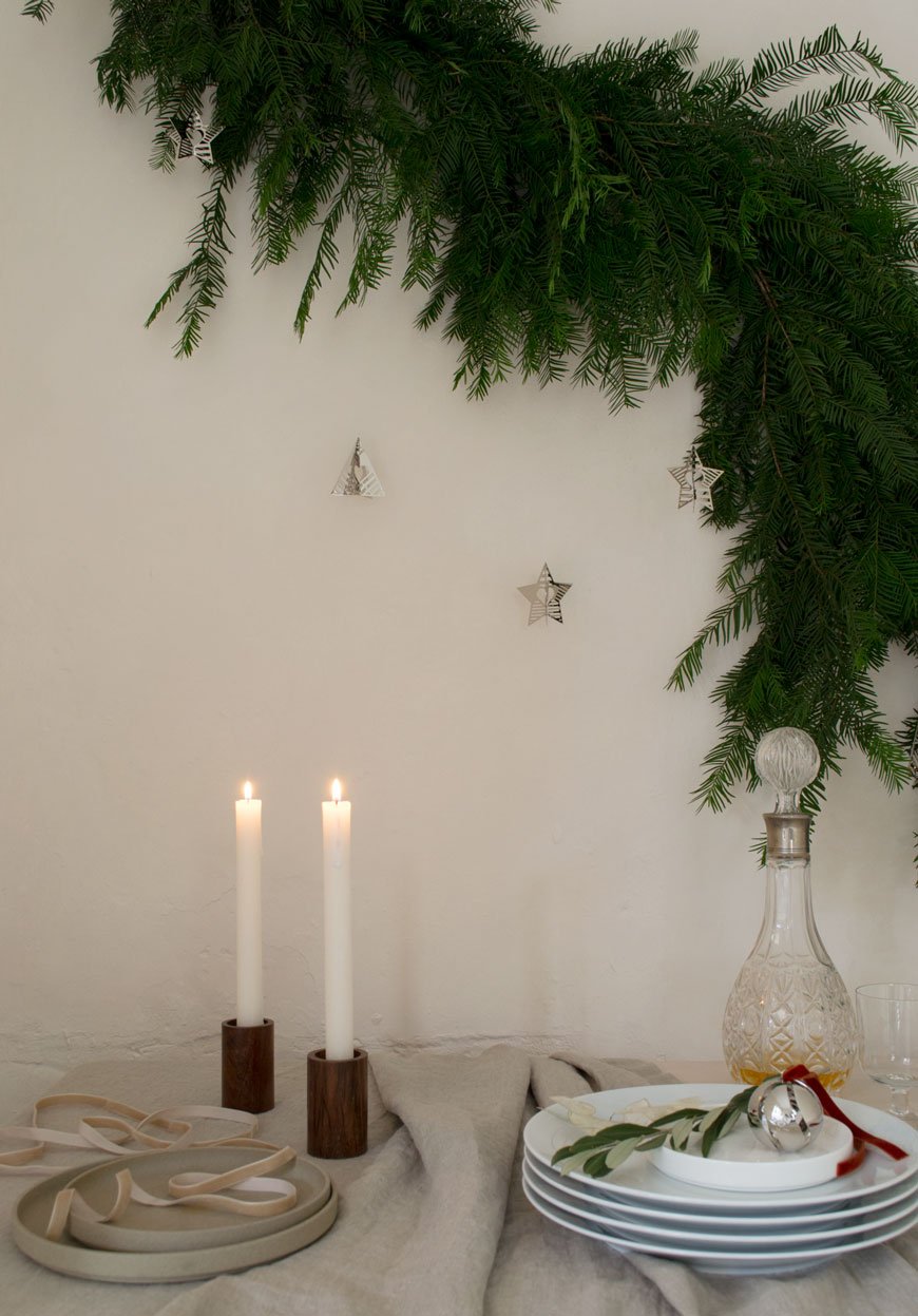 A warm, minimal Christmas dining table styled with a yew tree garland and the Georg Jensen Christmas Collectibles 2019. 