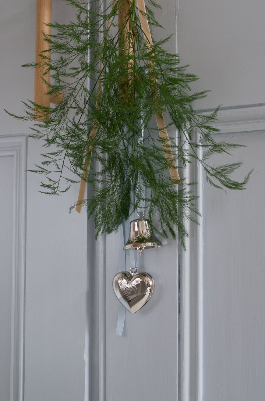 Sweet little festive details - a bunch of Christmas greenery tied with ribbon and little ornaments hung from a door handle. 