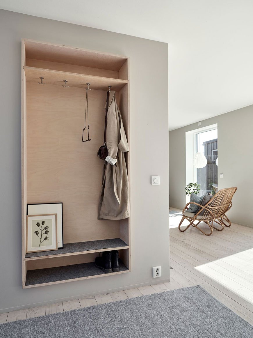 A wall mounted plywood open storage cupboard creates a hallway space in this architect designed family home in Sweden. 