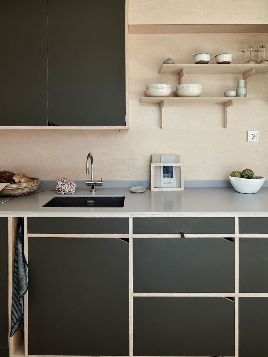 A contemporary, minimal plywood kitchen with dark green cabinets in an open plan architect designed family home in Sweden. 