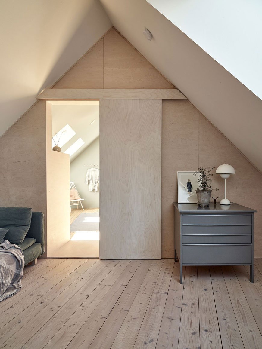 Looking into the bedroom with a plywood sliding door from the plywood clad snug of this architect designed Swedish island home.
