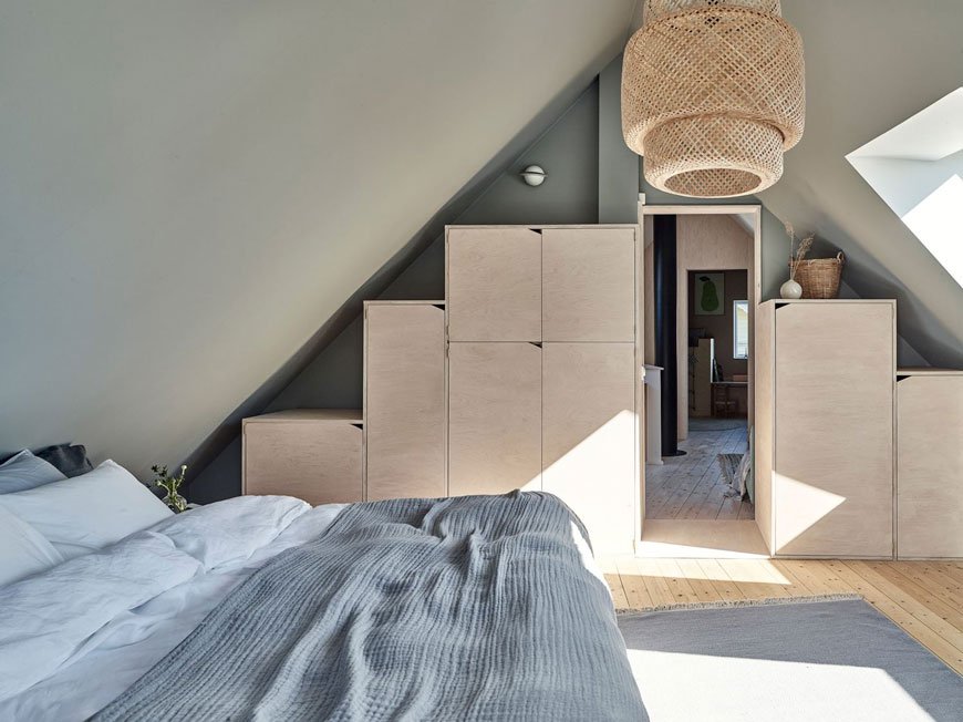 Built-in plywood box storage built into the eaves of this Scandinavian bedroom makes uses of the space. 