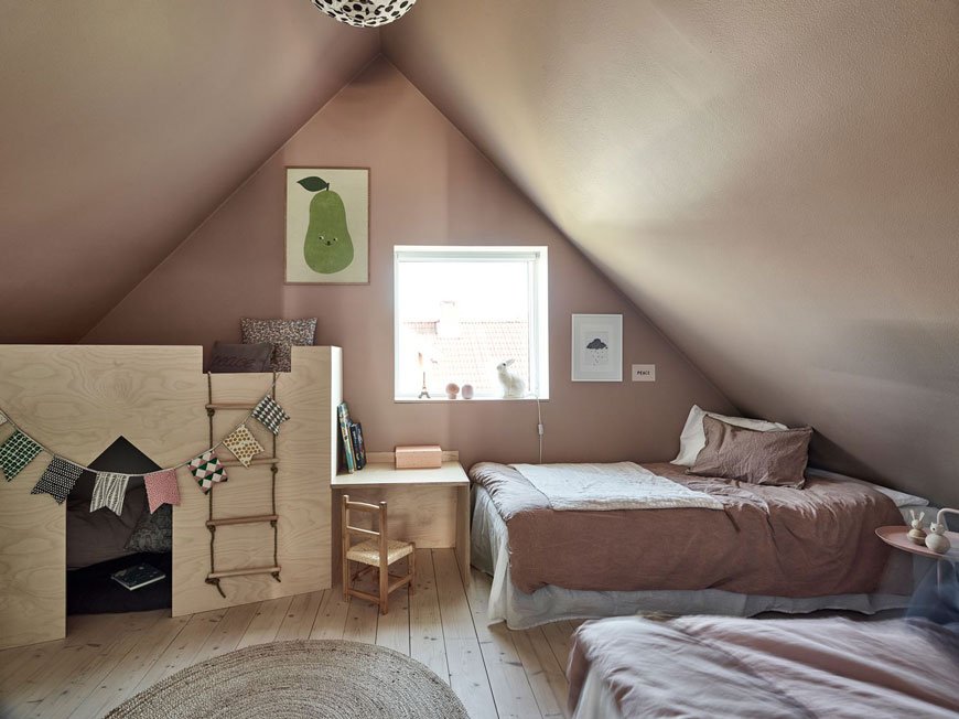 A soft pink and pine wood kids' bedroom in the eaves of an architect designed home has a sweet plywood 