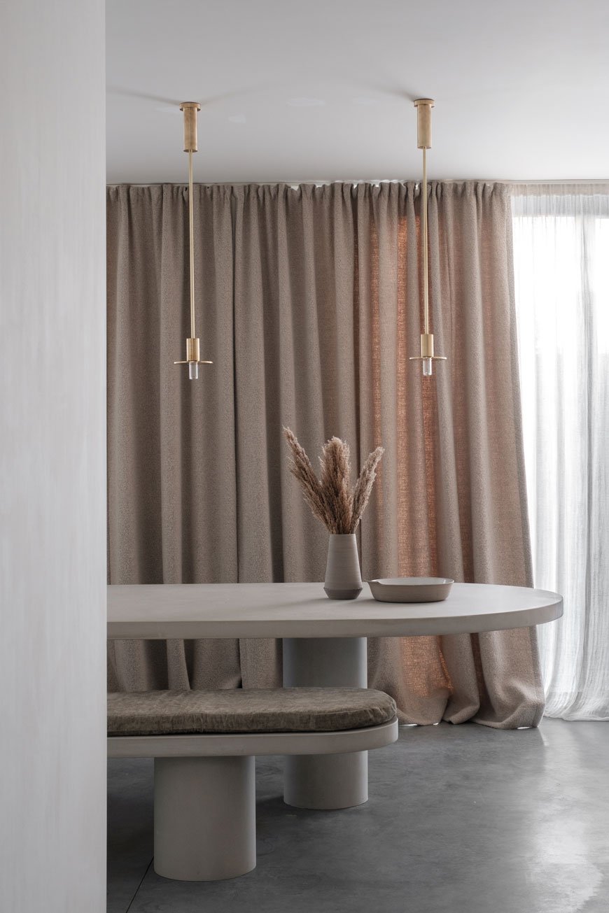 Full height natural linen curtains provide a contrast against a polished concrete floor in the kitchen dining room at Maison Jackie, Antwerp. 