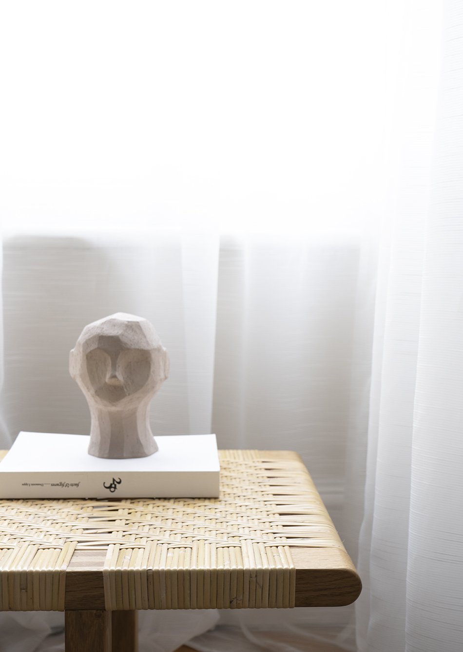 Olufemi concrete bust from Cooee Design on top of a rattan bench in a minimalist Nordic interior. 