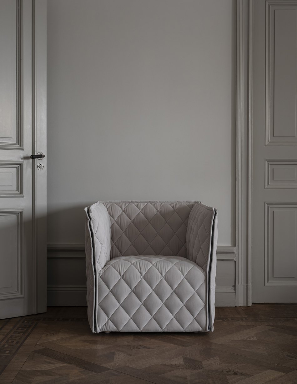 Gorgeous quilted lounge chair designed by Nina Jobs in a minimalist Scandinavian apartment with grey walls. 