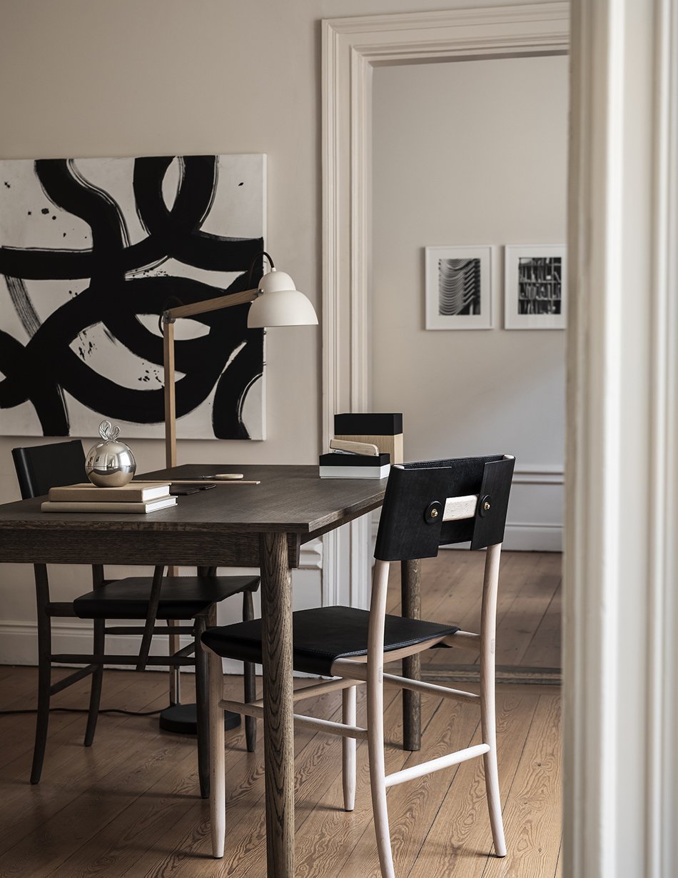 Abstract monochrome art and black leather Madonna chairs in a minimalist home office in Stockholm. 