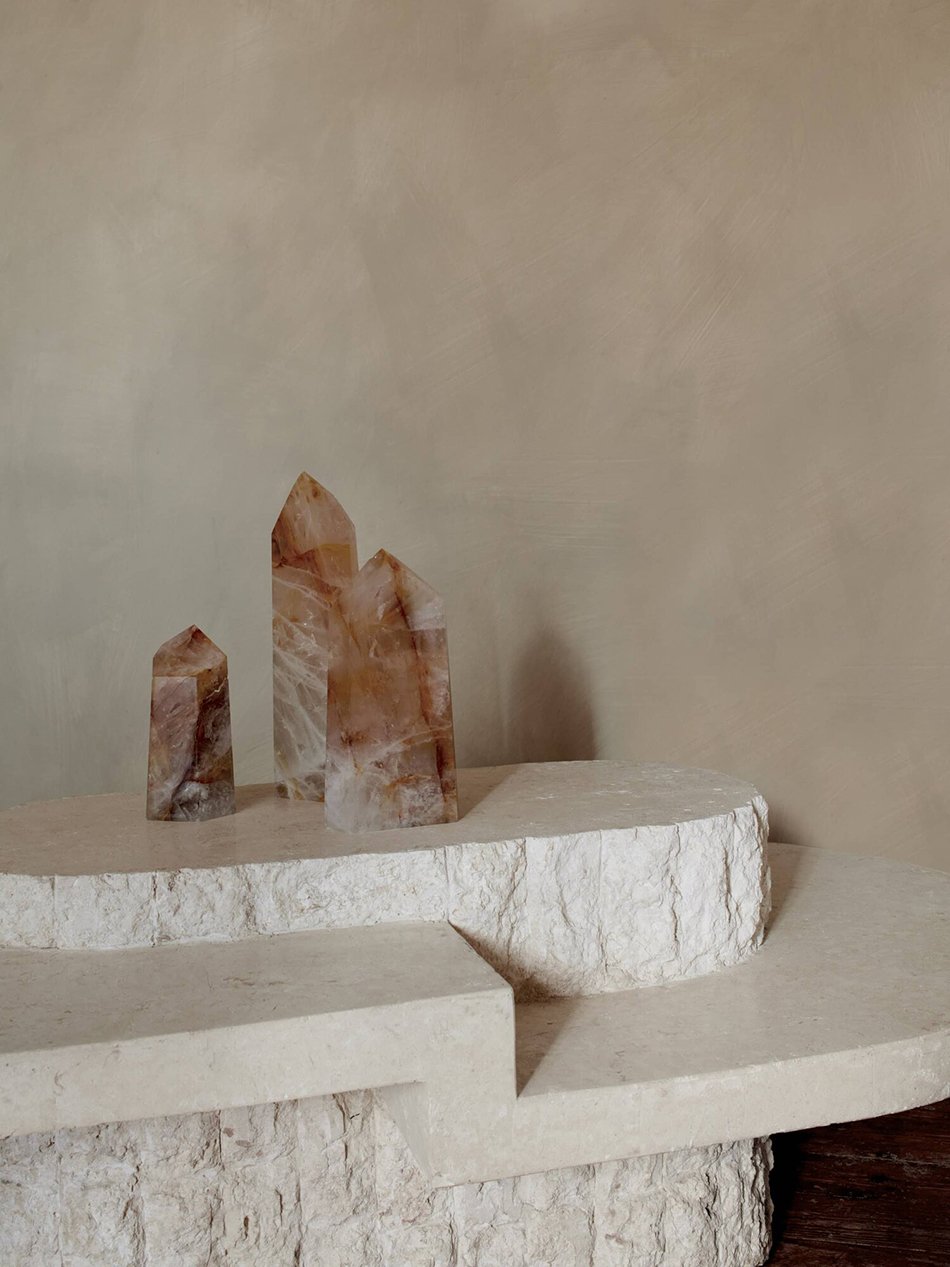 A grouping of crystals on a rough stone table against muted washed walls. 