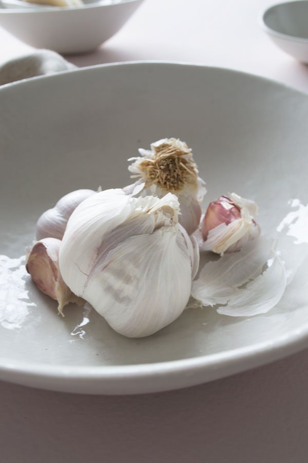 Blush pink garlic still life with soft pink and off-white ceramics