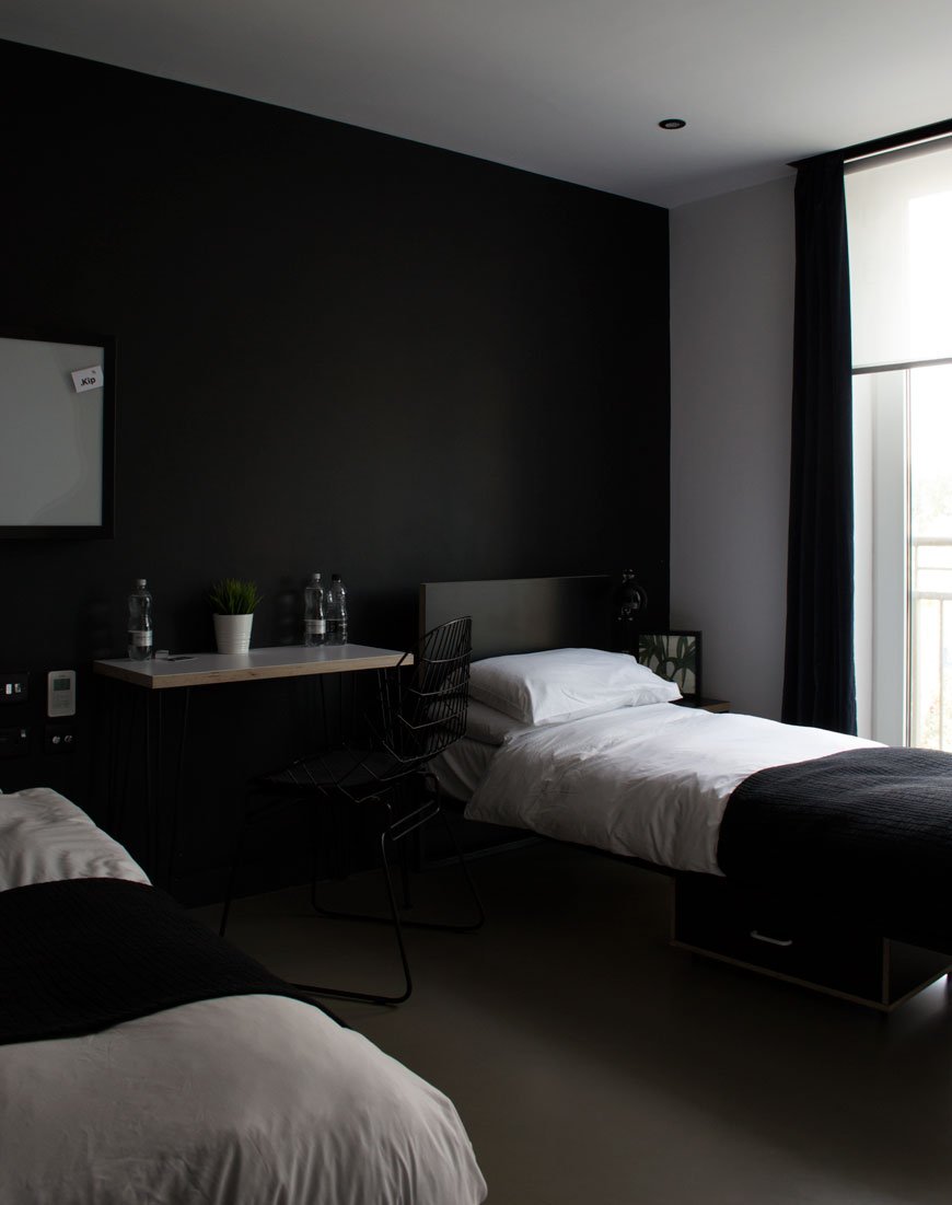 Black painted walls with white bedsheets at Kip Hotel, London