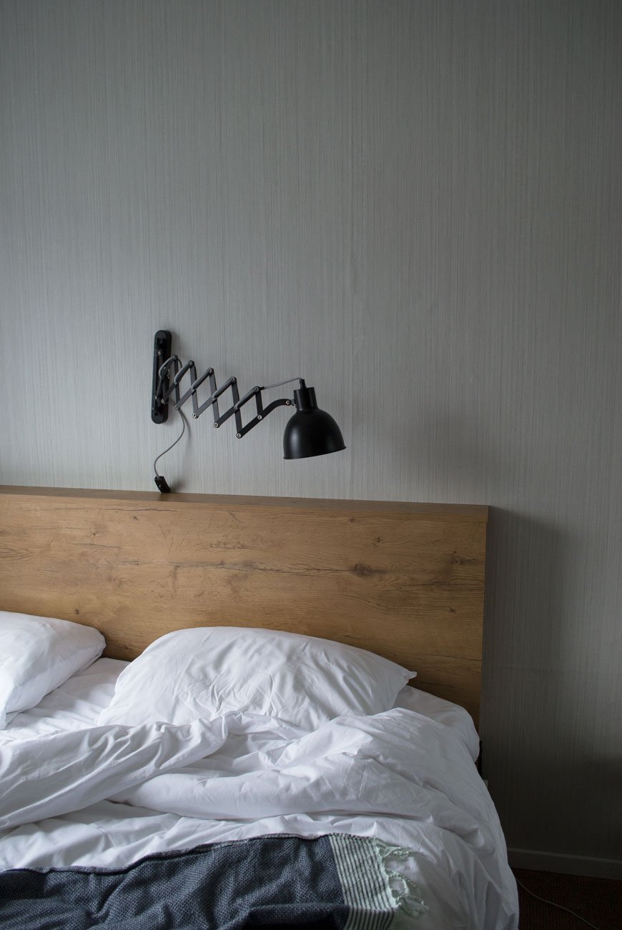 Wooden headboard and bedside lamp at The Good Hotel London.