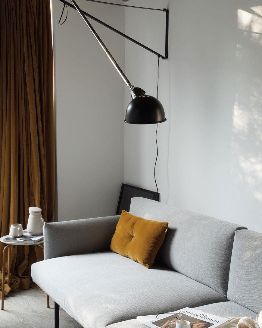 Flos 265 black wall light in a minimal living room with mustard curtains