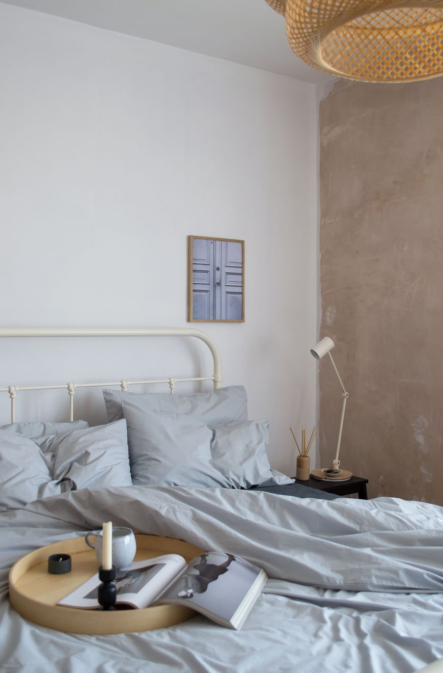 light bedroom with white and plaster pink walls and grey cotton sheets 