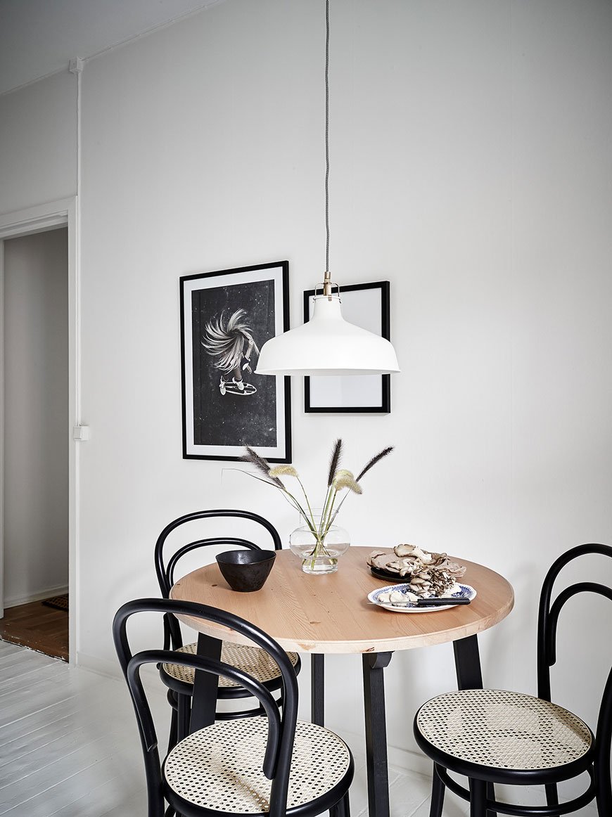 Three black cane Thonet bentwood chairs around a round table in a kitchen.