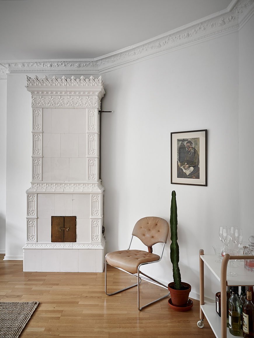 White tiled Swedish fireplace and bar cart in the living room of a Gothenburg apartment.