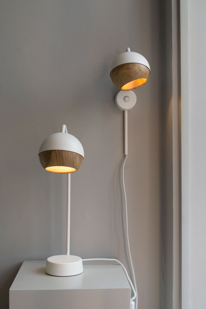 Two white and oak wall lamps on a grey wall at the Mater gallery. 