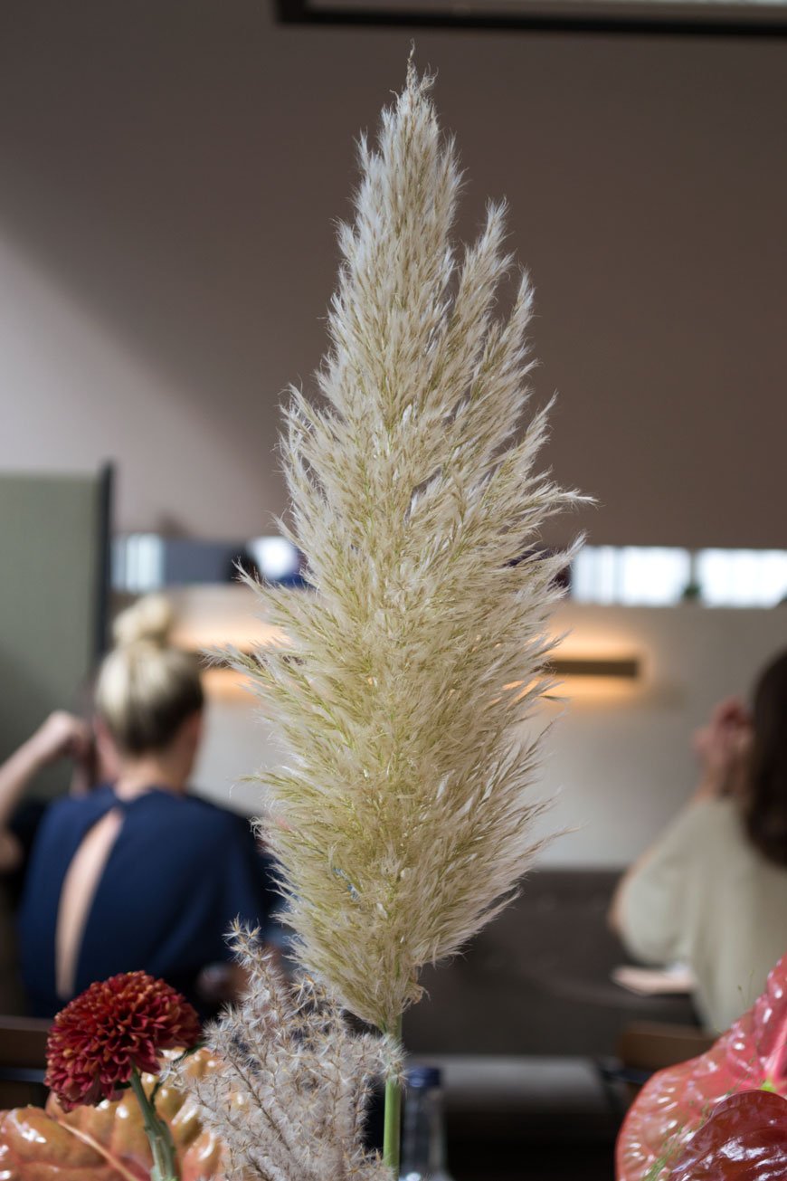 A lone pampas grass sits in a vase of textured flowers inside the STILL pop-up restaurant. 