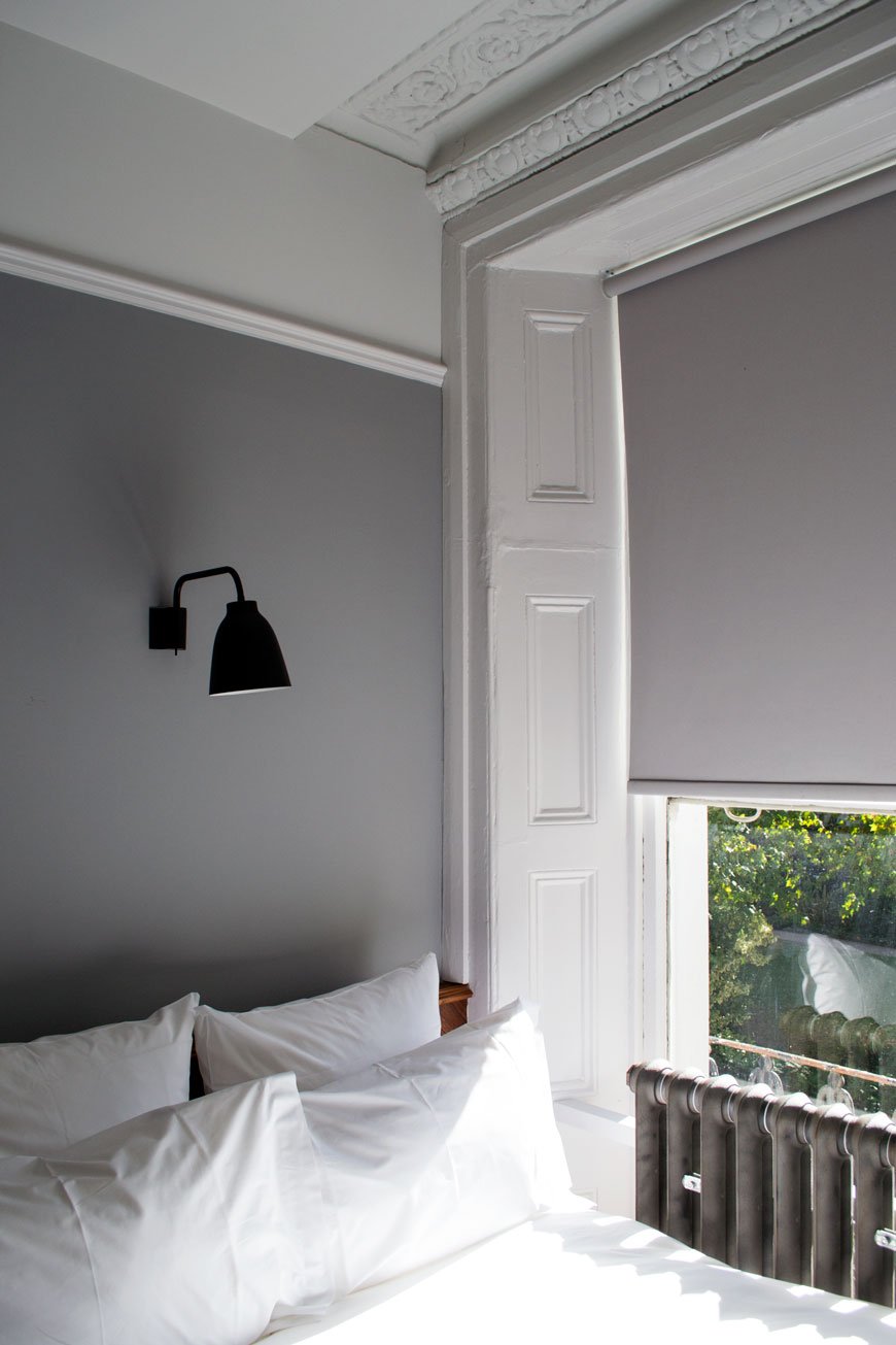 Grey and white Victorian bedroom with black wall lamp at The Pilgrm Hotel