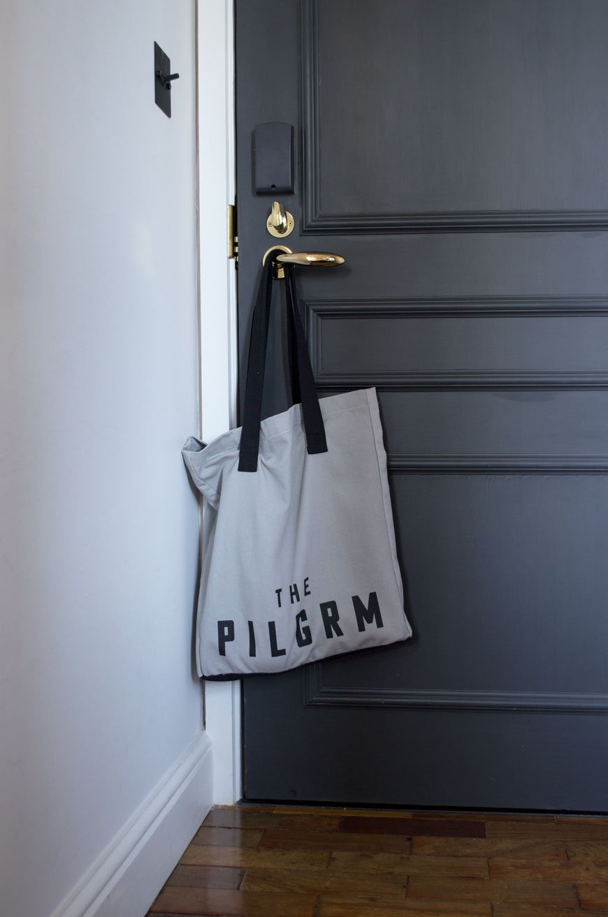 Custom The Pilgrm tote bag hanging on the door inside the bedroom. 