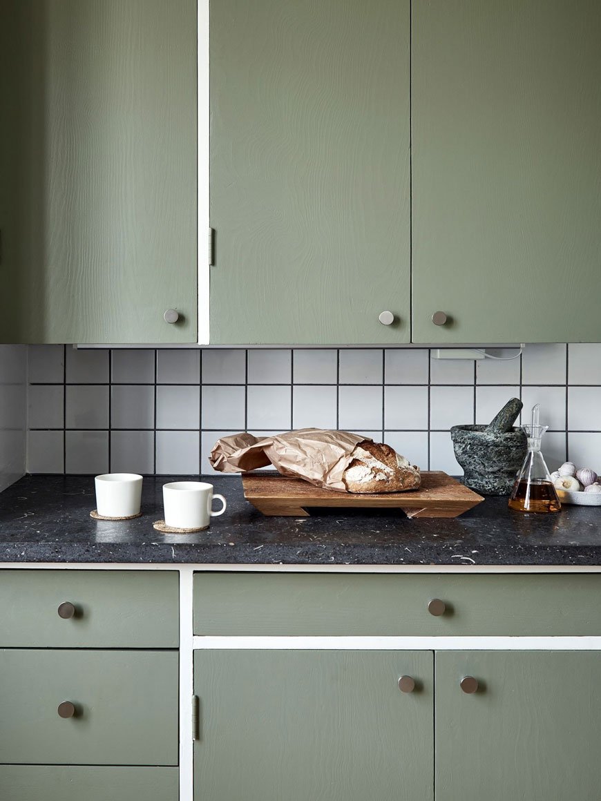 Coffee and toast on the slate worktop in this apartment with green kitchen units.