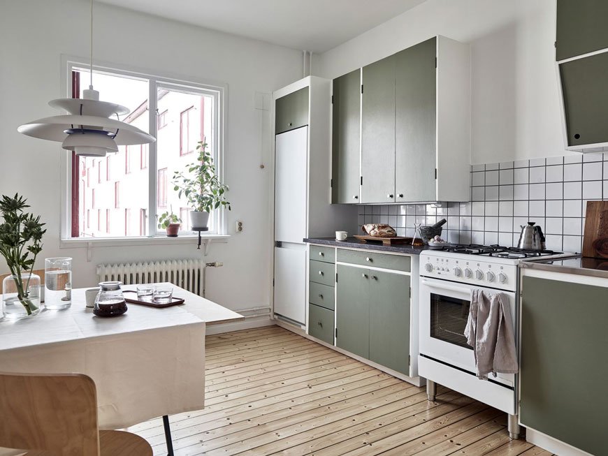 Inside a warm and inviting Gothenburg apartment with green kitchen units. 