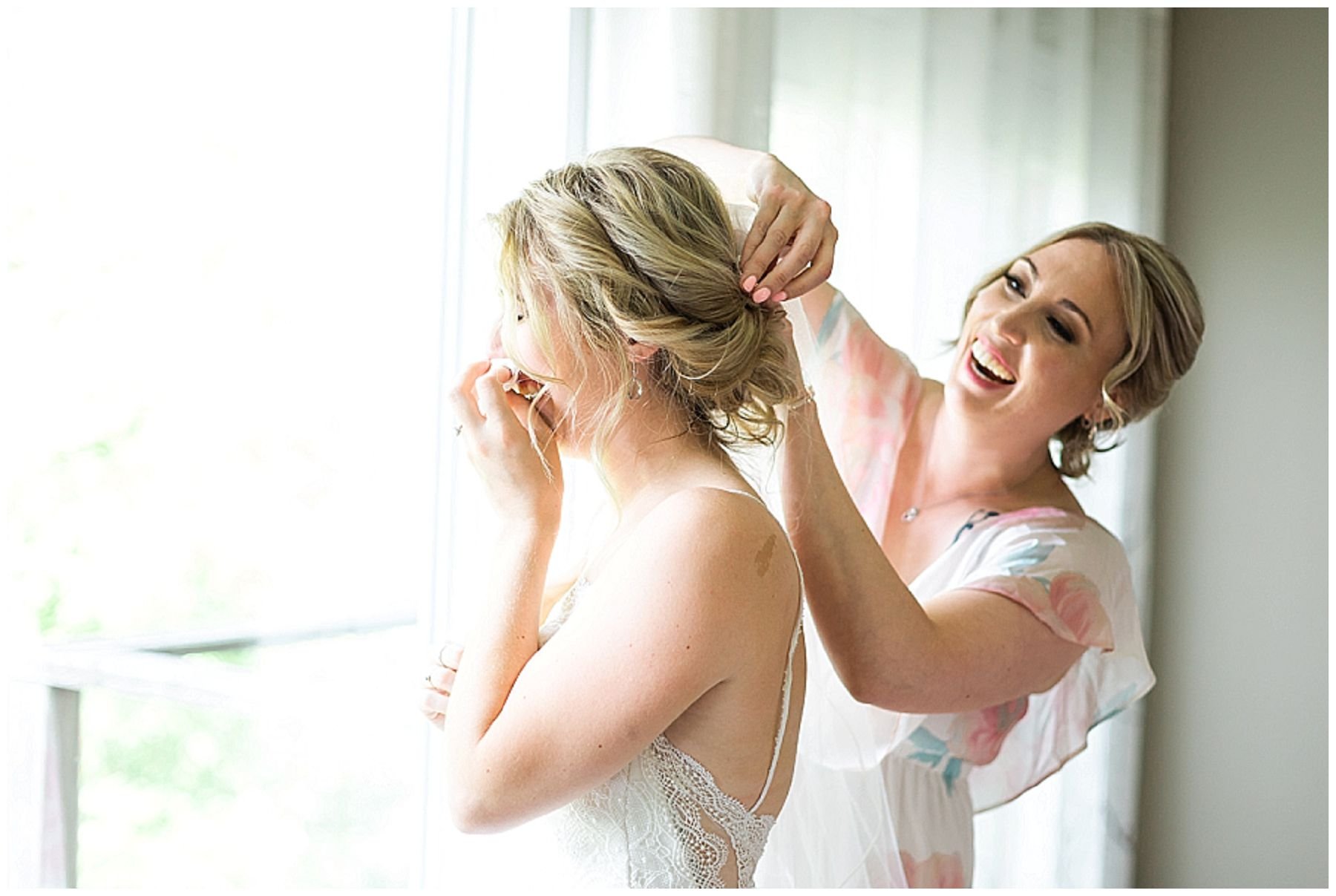Bride crying while maid of honor puts wedding veil on