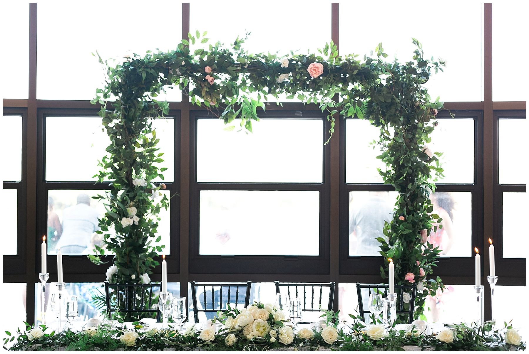Wedding table decor. Garland of greenery and white roses with candlesticks. With an arch of greenery. 
