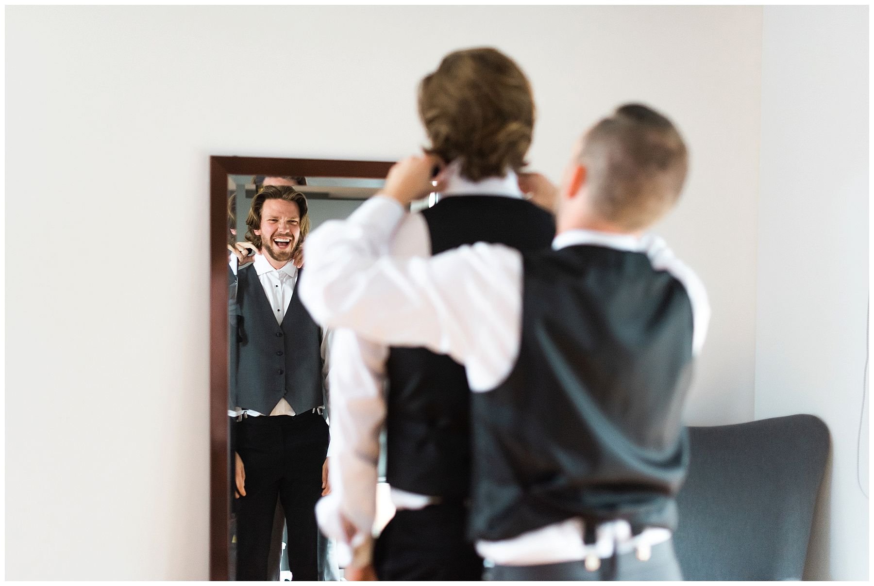 groom getting his suite jacket on by best man